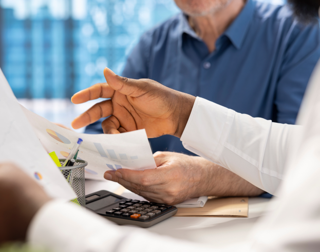 Profissionais discutindo relatórios financeiros em uma reunião de negócios, com gráficos e calculadora sobre a mesa, representando análise de dados e tomada de decisão estratégica