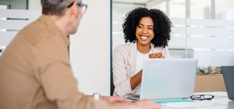 Profissionais sorridentes em uma reunião de trabalho, representando colaboração, comunicação e ambiente corporativo positivo